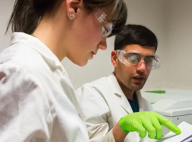 Two young scientists in lab coats having a discussion