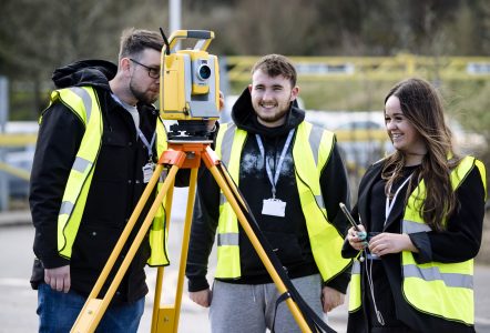 Three students using a laser level device