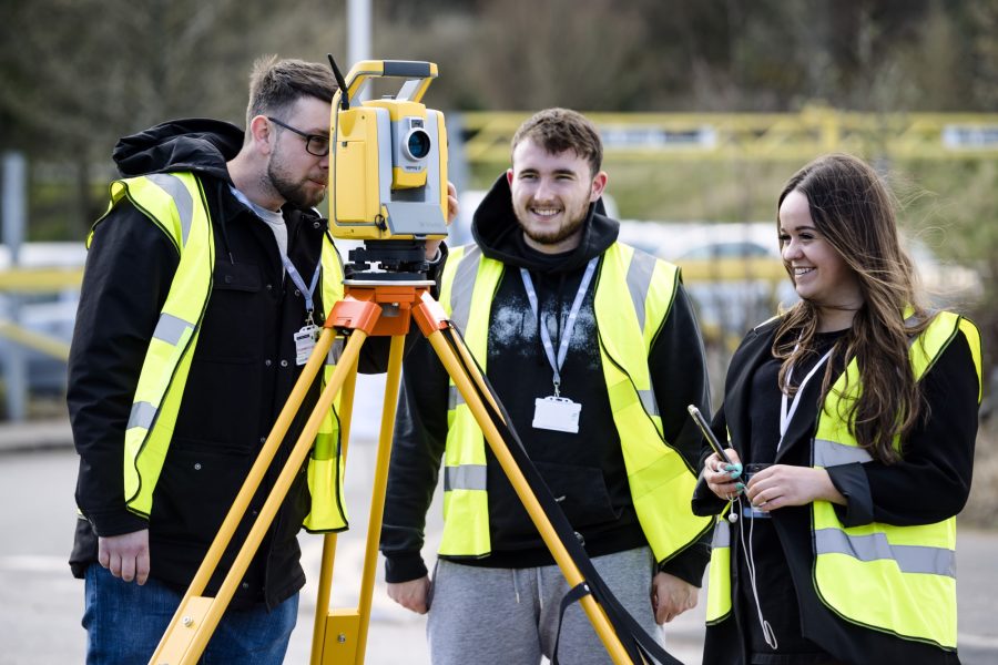 Three students using a laser level device