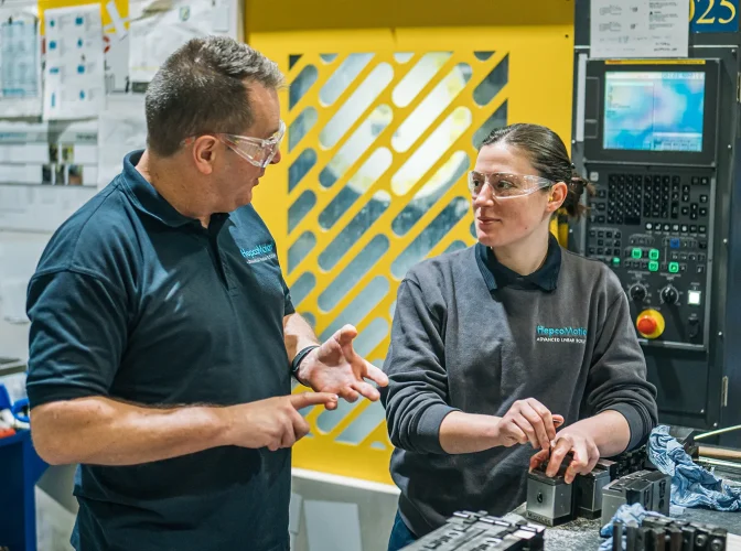 Two engineers on-site wearing goggles, discussing work