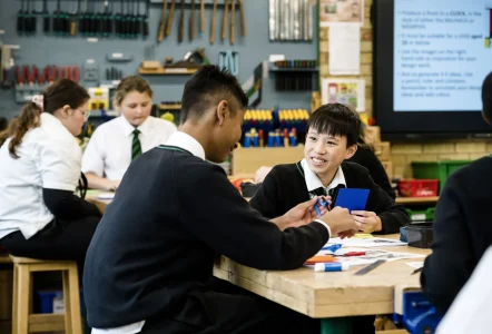 School students sitting at a desk in a design and technology classroom at school