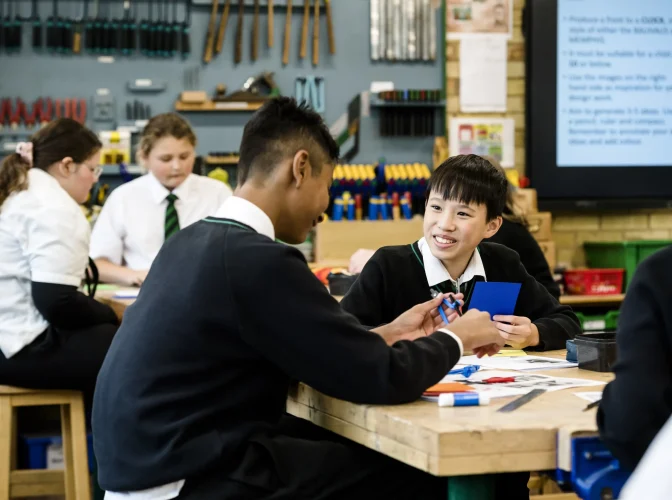 School students sitting at a desk in a design and technology classroom at school