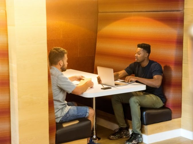 Two young men working on laptops