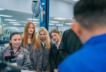 Engineering students in a factory environment, being given instruction
