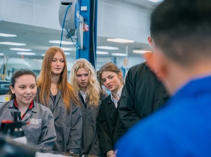 Engineering students in a factory environment, being given instruction