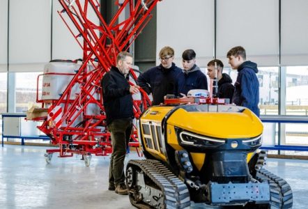 Four students listening to a teacher talk about a construction device