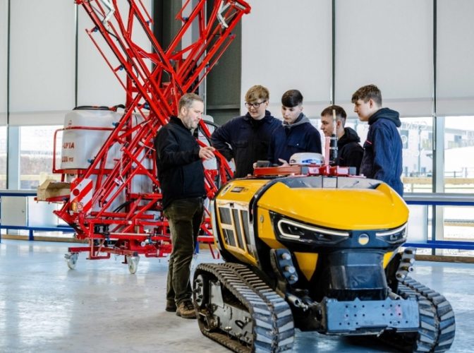 Four students listening to a teacher talk about a construction device