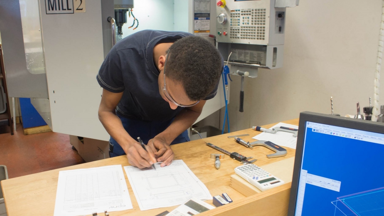 Male student working on technical drawing in engineering department at college